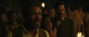 Movie still from “Palm Trees in the Snow” (2015), directed by Fernando González Molina – An old man with a beard and a yellow shirt; Close Up shot, Over the shoulder angle