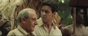 Movie still from “Palm Trees in the Snow” (2015), directed by Fernando González Molina – A man and an older man standing next to each other; Close Up shot, Over the shoulder angle