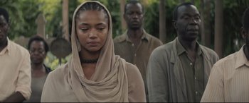 Movie still from “Palm Trees in the Snow” (2015), directed by Fernando González Molina – A woman in a head scarf is standing next to two other men; Close Up shot, Over the shoulder angle