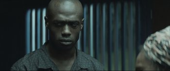 Movie still from “Palm Trees in the Snow” (2015), directed by Fernando González Molina – A man in a black shirt is looking at the camera; Close Up shot, Low angle