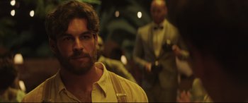 Movie still from “Palm Trees in the Snow” (2015), directed by Fernando González Molina – A person wearing a suit and tie; Close Up shot, Over the shoulder angle