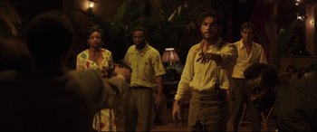 Movie still from “Palm Trees in the Snow” (2015), directed by Fernando González Molina – A group of people standing in front of a lamp; Medium shot, Over the shoulder angle