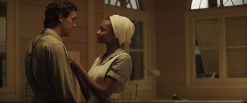 Movie still from “Palm Trees in the Snow” (2015), directed by Fernando González Molina – A man and a woman standing next to each other in front of a window; Medium shot, Over the shoulder angle