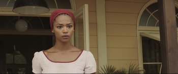 Movie still from “Palm Trees in the Snow” (2015), directed by Fernando González Molina – A woman with a red headscarf standing in front of a house; Close Up shot, Low angle