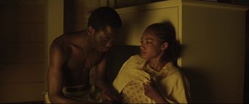 Movie still from “Palm Trees in the Snow” (2015), directed by Fernando González Molina – A man and a woman sitting on a couch; Medium shot, High angle