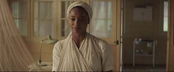 Movie still from “Palm Trees in the Snow” (2015), directed by Fernando González Molina – A woman with a head scarf is standing in front of a window; Close Up shot, Over the shoulder angle