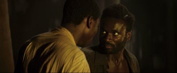 Movie still from “Palm Trees in the Snow” (2015), directed by Fernando González Molina – Two men are looking at each other in the dark; Close Up shot, Over the shoulder angle