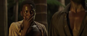 Movie still from “Palm Trees in the Snow” (2015), directed by Fernando González Molina – A man standing next to a tree with his hand over his mouth; Close Up shot, Over the shoulder angle