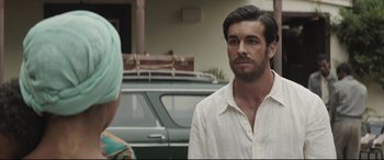 Movie still from “Palm Trees in the Snow” (2015), directed by Fernando González Molina – A man standing next to a woman in front of a car; Close Up shot, Over the shoulder angle