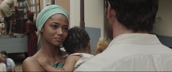 Movie still from “Palm Trees in the Snow” (2015), directed by Fernando González Molina – A woman with a green headscarf is holding a baby; Close Up shot, Over the shoulder angle