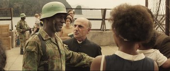 Movie still from “Palm Trees in the Snow” (2015), directed by Fernando González Molina – A man wearing a green helmet talks to a man in a black shirt; Medium shot, Over the shoulder angle