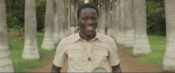 Movie still from “Palm Trees in the Snow” (2015), directed by Fernando González Molina – A man smiling while holding a frisbee in his hand; Close Up shot, High angle