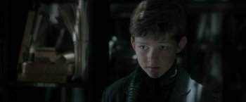 Movie still from “Pan” (2015), directed by Joe Wright – A young boy wearing a black jacket and a green scarf; Close Up shot, Over the shoulder angle