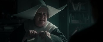 Movie still from “Pan” (2015), directed by Joe Wright – An old woman wearing a white hat and a green robe; Close Up shot, Over the shoulder angle