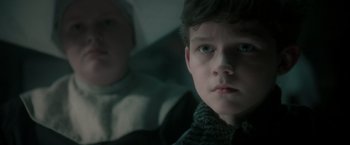 Movie still from “Pan” (2015), directed by Joe Wright – A young boy looking at the camera while a younger person looks on; Close Up shot, Over the shoulder angle
