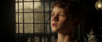 Movie still from “Pan” (2015), directed by Joe Wright – A young boy with blue eyes stares into the distance; Close Up shot, Low angle