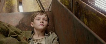 Movie still from “Pan” (2015), directed by Joe Wright – A young boy laying on the ground looking up at the sky; Close Up shot, Overhead angle