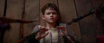 Movie still from “Pan” (2015), directed by Joe Wright – A young boy holding a pair of knifes in front of him; Close Up shot, High angle