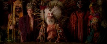Movie still from “Pan” (2015), directed by Joe Wright – An old man with a long white beard wearing a large feather headdress; Medium shot, Overhead angle
