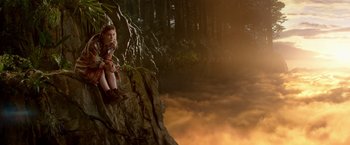 Movie still from “Pan” (2015), directed by Joe Wright – A young girl sitting on top of a rock near a body of water; Wide shot, High angle