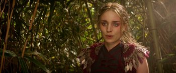 Movie still from “Pan” (2015), directed by Joe Wright – A young woman in a red and black dress in front of a tree; Close Up shot, Over the shoulder angle