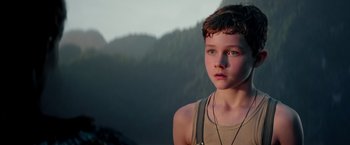 Movie still from “Pan” (2015), directed by Joe Wright – A young boy is standing in front of some mountains; Close Up shot, Low angle