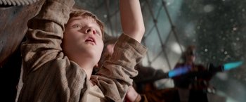 Movie still from “Pan” (2015), directed by Joe Wright – A young boy raising his arm up in the air; Close Up shot, Low angle