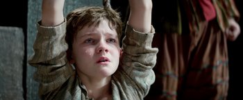 Movie still from “Pan” (2015), directed by Joe Wright – A young boy is crying while holding his arms up; Close Up shot, High angle