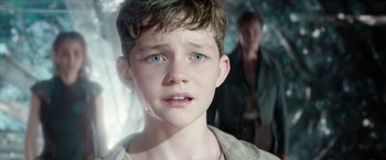 Movie still from “Pan” (2015), directed by Joe Wright – A young boy with blue eyes stares into the camera; Close Up shot, Over the shoulder angle