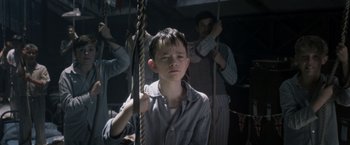 Movie still from “Pan” (2015), directed by Joe Wright – A young boy is hanging from a rope; Medium shot, Low angle