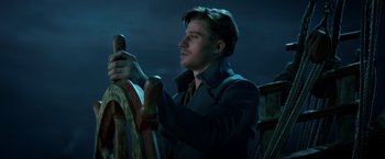 Movie still from “Pan” (2015), directed by Joe Wright – A man holding a steering wheel in the dark at night; Close Up shot, Low angle