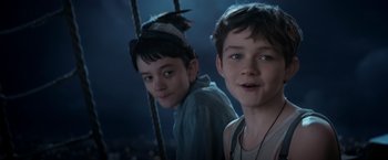 Movie still from “Pan” (2015), directed by Joe Wright – Two young boys standing next to each other on a swing; Close Up shot, High angle