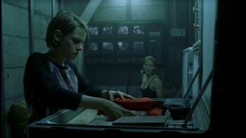 Movie still from “Panic Room” (2002), directed by David Fincher – Two people sitting at a table in front of computers; Medium shot, Low angle
