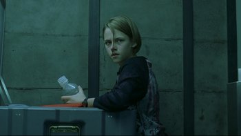 Movie still from “Panic Room” (2002), directed by David Fincher – A young girl sitting on a table holding a plastic bottle; Medium shot, Low angle