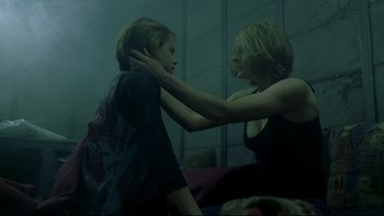 Movie still from “Panic Room” (2002), directed by David Fincher – A woman holding a young boy's head in a dark room; Medium shot, Low angle