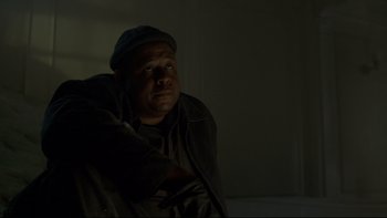 Movie still from “Panic Room” (2002), directed by David Fincher – A man sitting on a couch in a dark room; Close Up shot, Low angle