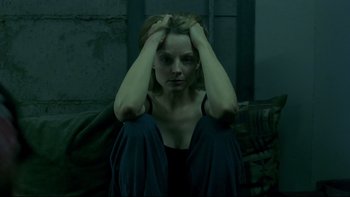 Movie still from “Panic Room” (2002), directed by David Fincher – A woman sitting on a couch holding her head in her hands; Medium shot, High angle