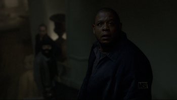 Movie still from “Panic Room” (2002), directed by David Fincher – A man standing in a dark room looking at the camera; Medium shot, Over the shoulder angle