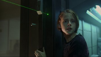Movie still from “Panic Room” (2002), directed by David Fincher – A young girl looking out of a window at a green laser beam; Medium shot, Low angle