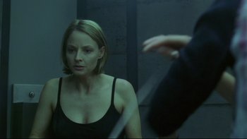 Movie still from “Panic Room” (2002), directed by David Fincher – A woman in a black tank top looking in a mirror; Medium shot, Over the shoulder angle