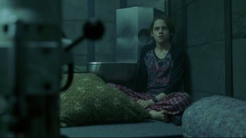 Movie still from “Panic Room” (2002), directed by David Fincher – A girl sitting on the ground in a room; Medium shot, High angle