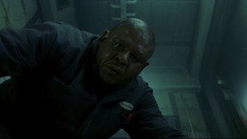 Movie still from “Panic Room” (2002), directed by David Fincher – A man in a dark room with a sign on his chest; Close Up shot, Low angle