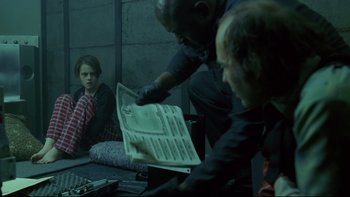 Movie still from “Panic Room” (2002), directed by David Fincher – A man is looking at a newspaper while another man watches; Medium shot, Over the shoulder angle