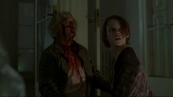 Movie still from “Panic Room” (2002), directed by David Fincher – A woman holding a man's arm with blood on his face; Medium shot, Over the shoulder angle