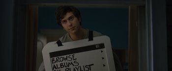 Movie still from “Paper Towns” (2015), directed by Jake Schreier – A young man holding up a sign that reads " browse albums vs; Close Up shot, Over the shoulder angle