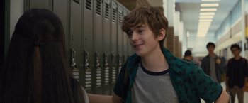 Movie still from “Paper Towns” (2015), directed by Jake Schreier – A young man standing in front of lockers in a school hallway; Close Up shot, Over the shoulder angle