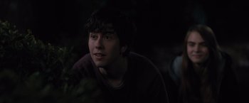 Movie still from “Paper Towns” (2015), directed by Jake Schreier – A young man is sitting in the dark looking at the camera; Close Up shot, Over the shoulder angle