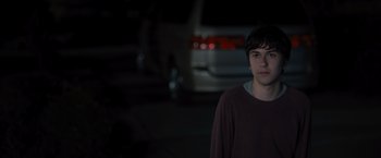 Movie still from “Paper Towns” (2015), directed by Jake Schreier – A young man standing in a parking lot at night; Medium shot, Over the shoulder angle