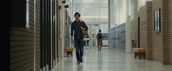 Movie still from “Paper Towns” (2015), directed by Jake Schreier – A man walking down a hallway with a bag in his hand; Wide shot, Low angle