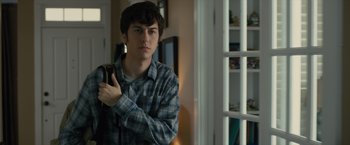 Movie still from “Paper Towns” (2015), directed by Jake Schreier – A young man holding a cell phone in his hand; Close Up shot, Over the shoulder angle